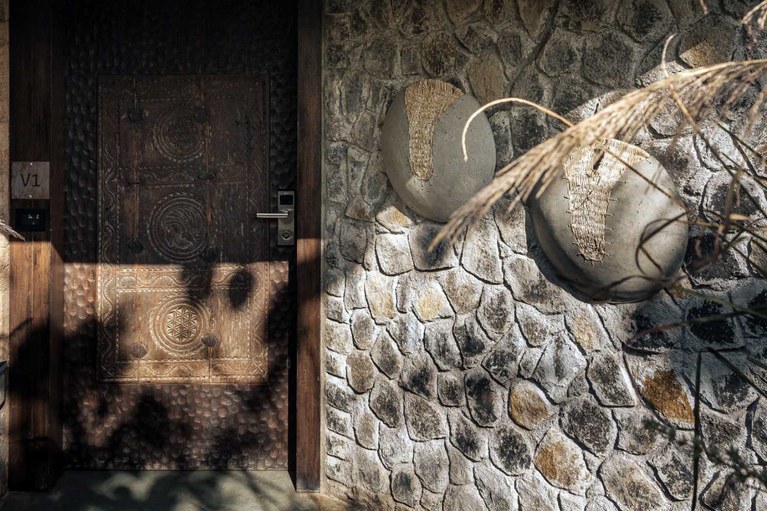 Hand-fitted stone masonry, terracotta ceiling and carved timber door at a Tipai forest villa